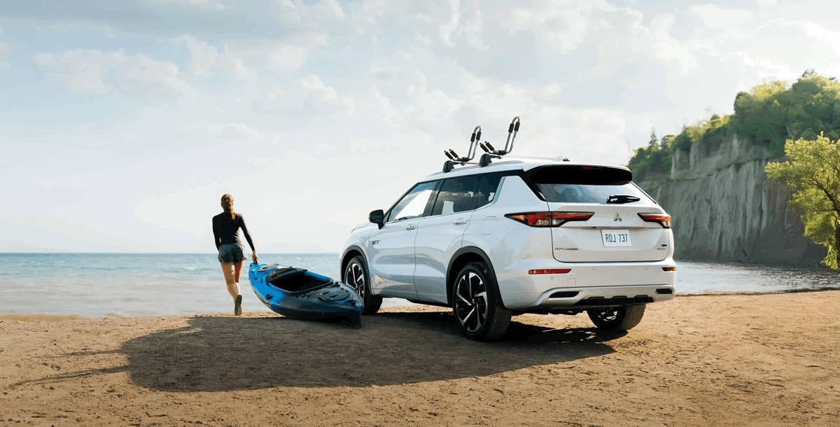 Vue 3/4 arrière d'un Mitsubishi Outlander PHEV 2025 sur une plage.