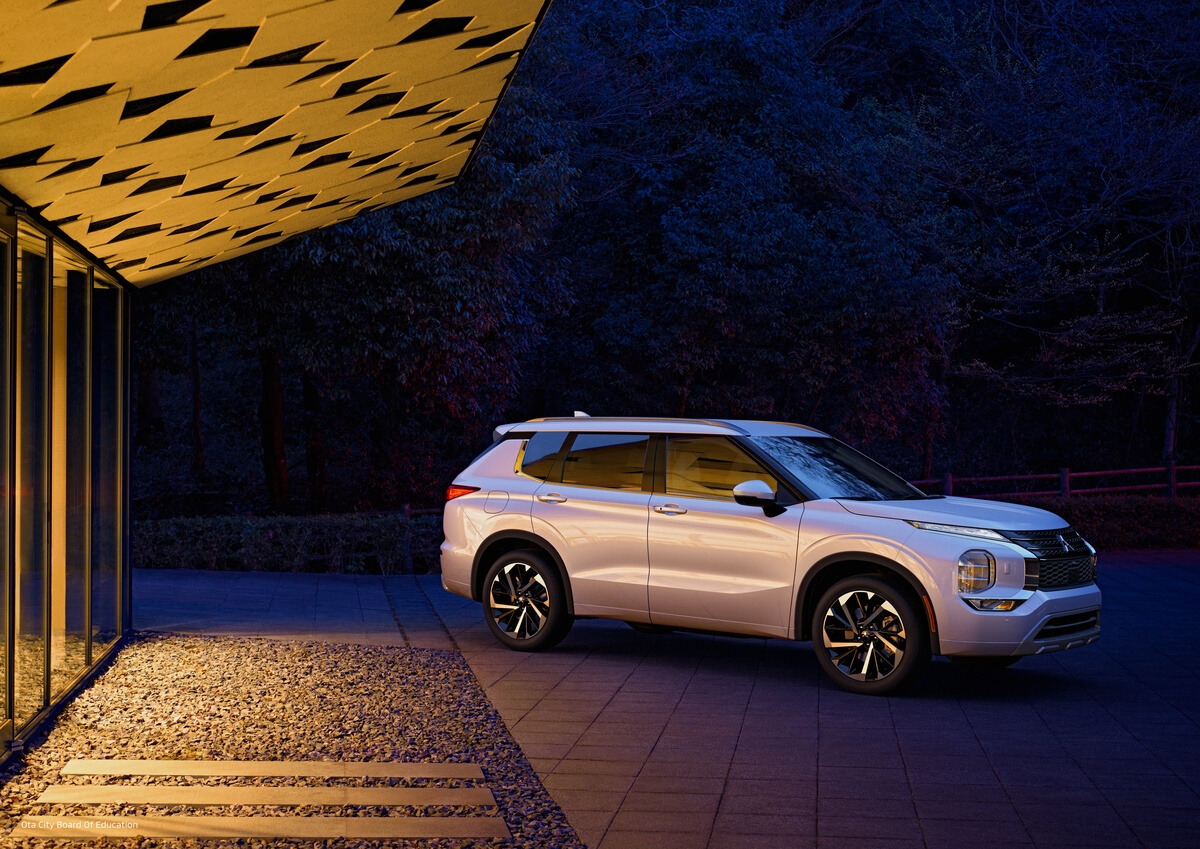 vue latérale du Mitsubishi Outlander 2022 stationné proche d'un bâtiment le soir