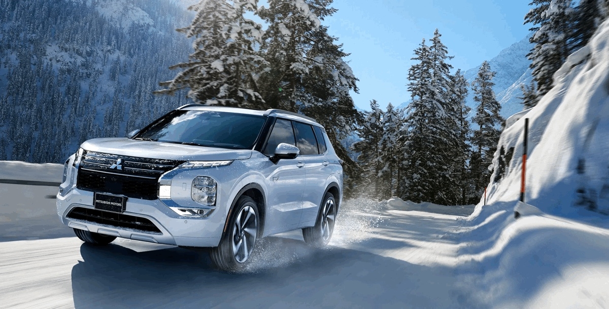 Vue 3/4 avant du Mitsubishi Outlander PHEV 2025 conduisant dans des conditions routières de neige.