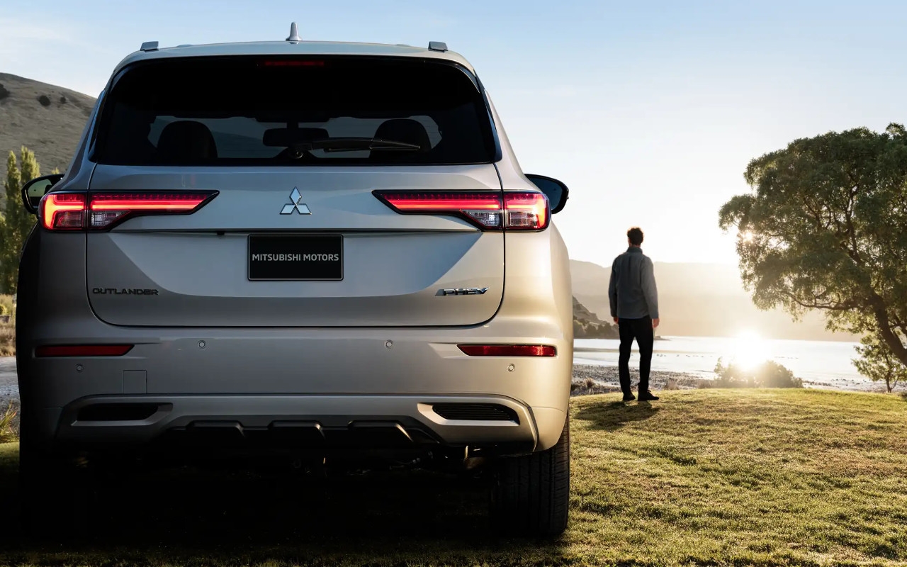 Vue arrière du Mitsubishi Outlander PHEV garé sur un terrain en nature.